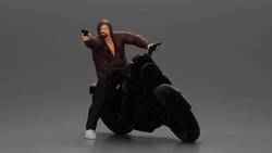 Hooded gangster man sits on motorcycle aiming a pistol